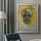 Expressive skull study painting by Vincent van Gogh in an ornate champagne frame displayed in a neutral interior setting.