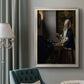 Quiet interior genre scene of a woman with scales by Johannes Vermeer in an ornate champagne frame displayed in a neutral interior setting.