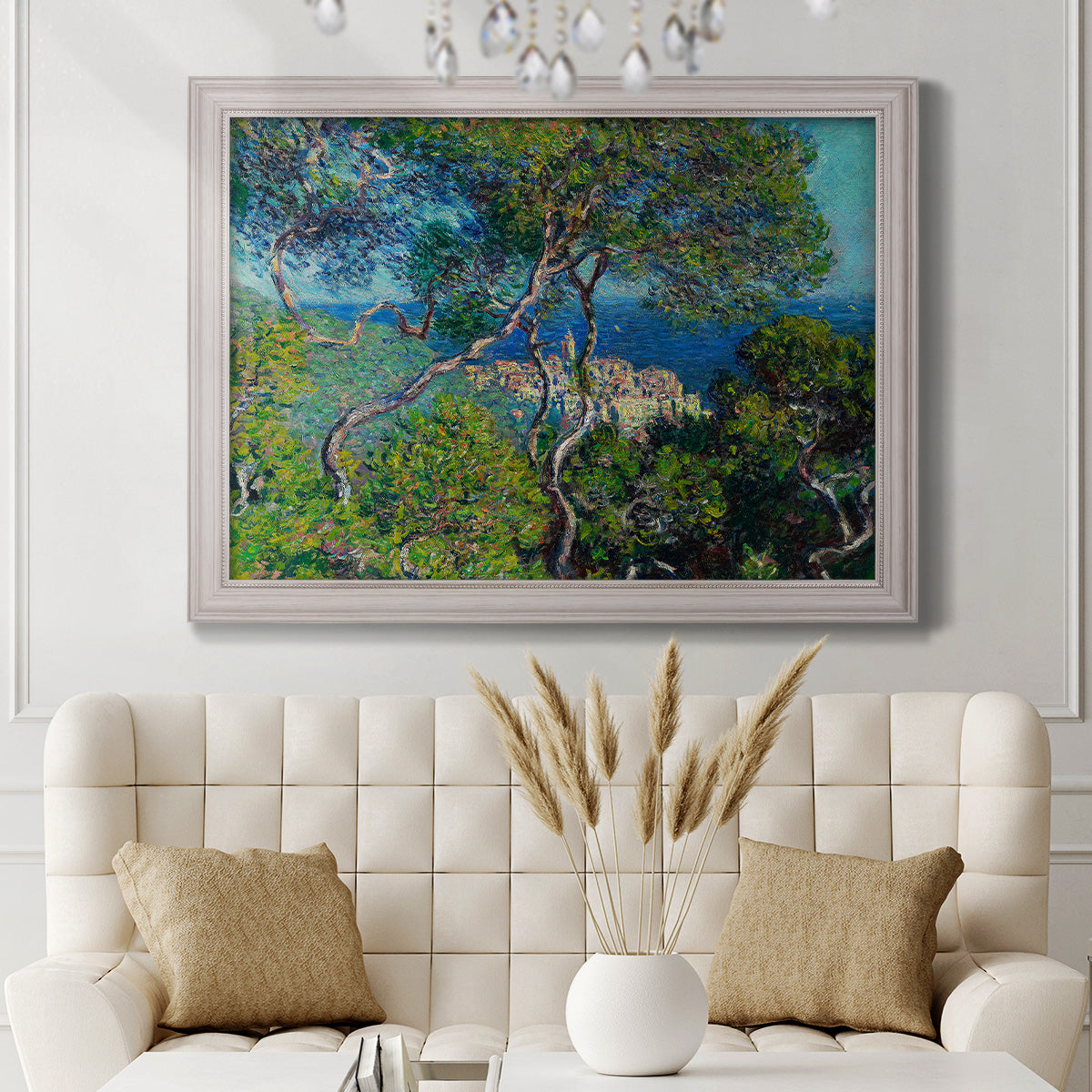 Impressionist Mediterranean coastal landscape by Claude Monet in an ornate weathered white frame displayed in a neutral-toned interior setting.