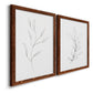 Angled view of a set of two maple barnwood framed canvas prints featuring two minimalist botanical line drawings featuring single continuous-line leafy branches.