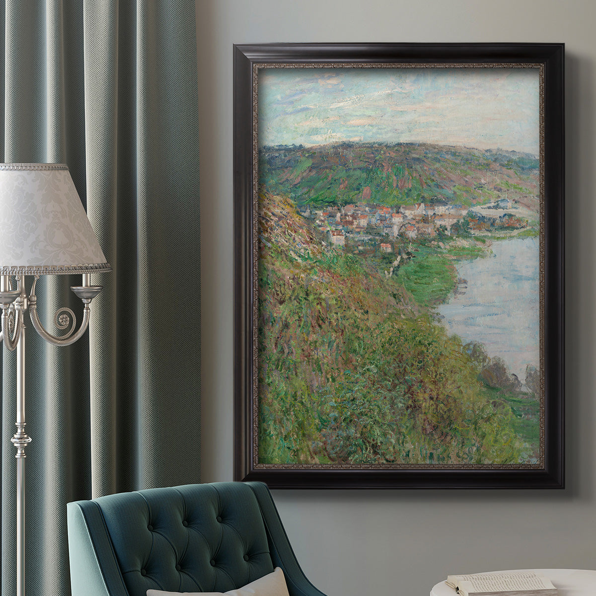 Impressionist landscape view of Vétheuil by Claude Monet in an ornate black frame with gilded inner detail displayed in a neutral interior setting.