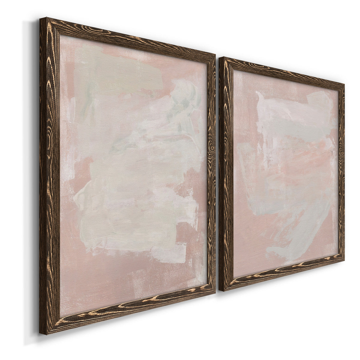 Angled view of a set of two walnut barnwood framed canvas prints featuring two minimalist color-field abstracts featuring soft blush and white painterly fields.