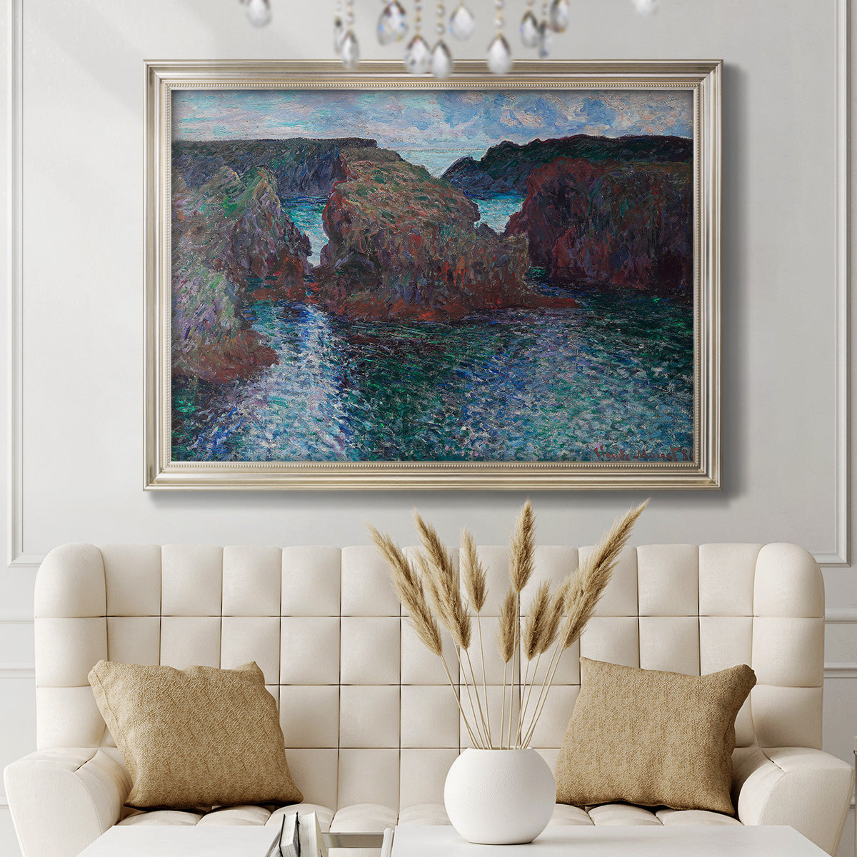Impressionist rocky seascape by Claude Monet in an ornate champagne frame displayed in a neutral-toned interior setting.
