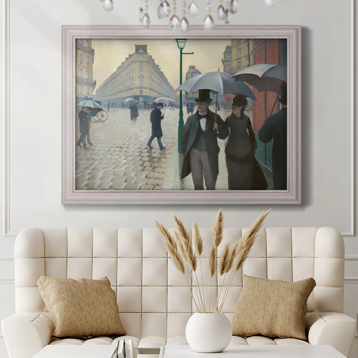Impressionist urban street scene in the rain by Gustave Caillebotte in an ornate weathered white frame displayed in a neutral-toned interior setting.