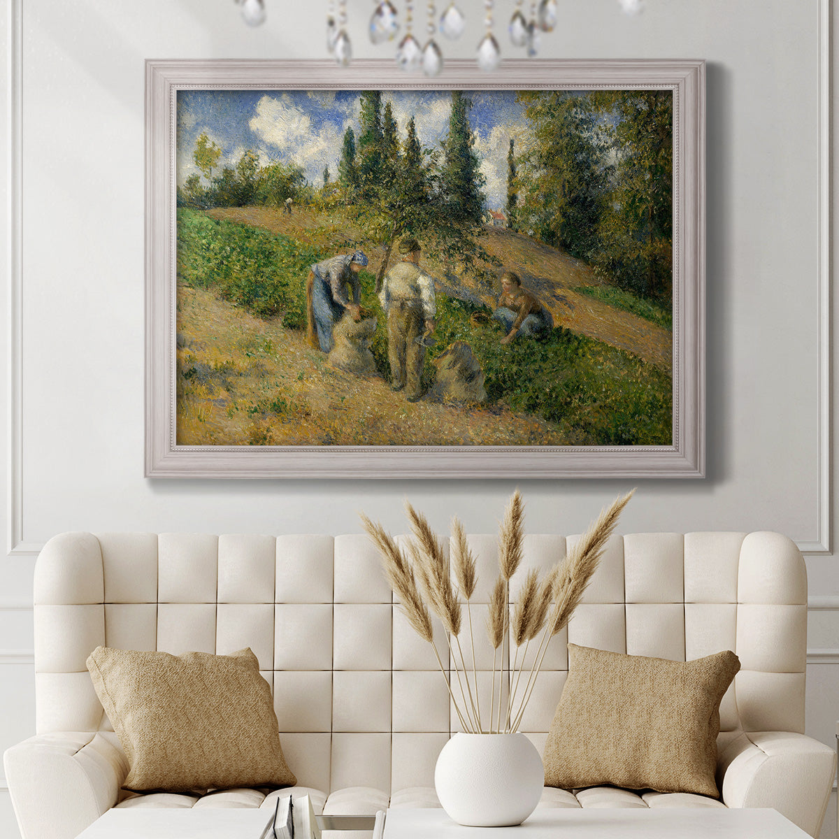 Impressionist countryside harvest scene by Camille Pissarro in an ornate weathered white frame displayed in a neutral-toned interior setting.