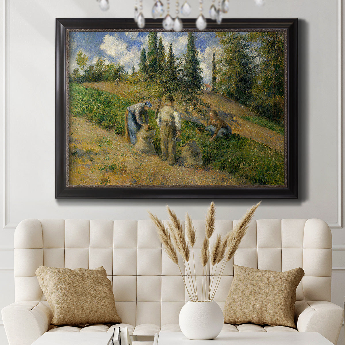 Impressionist countryside harvest scene by Camille Pissarro in an ornate black frame with gilded inner detail displayed in a neutral-toned interior setting.