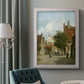 Rustic European street scene painting by Adriaan Eversen in an ornate weathered white frame displayed in a neutral interior setting.