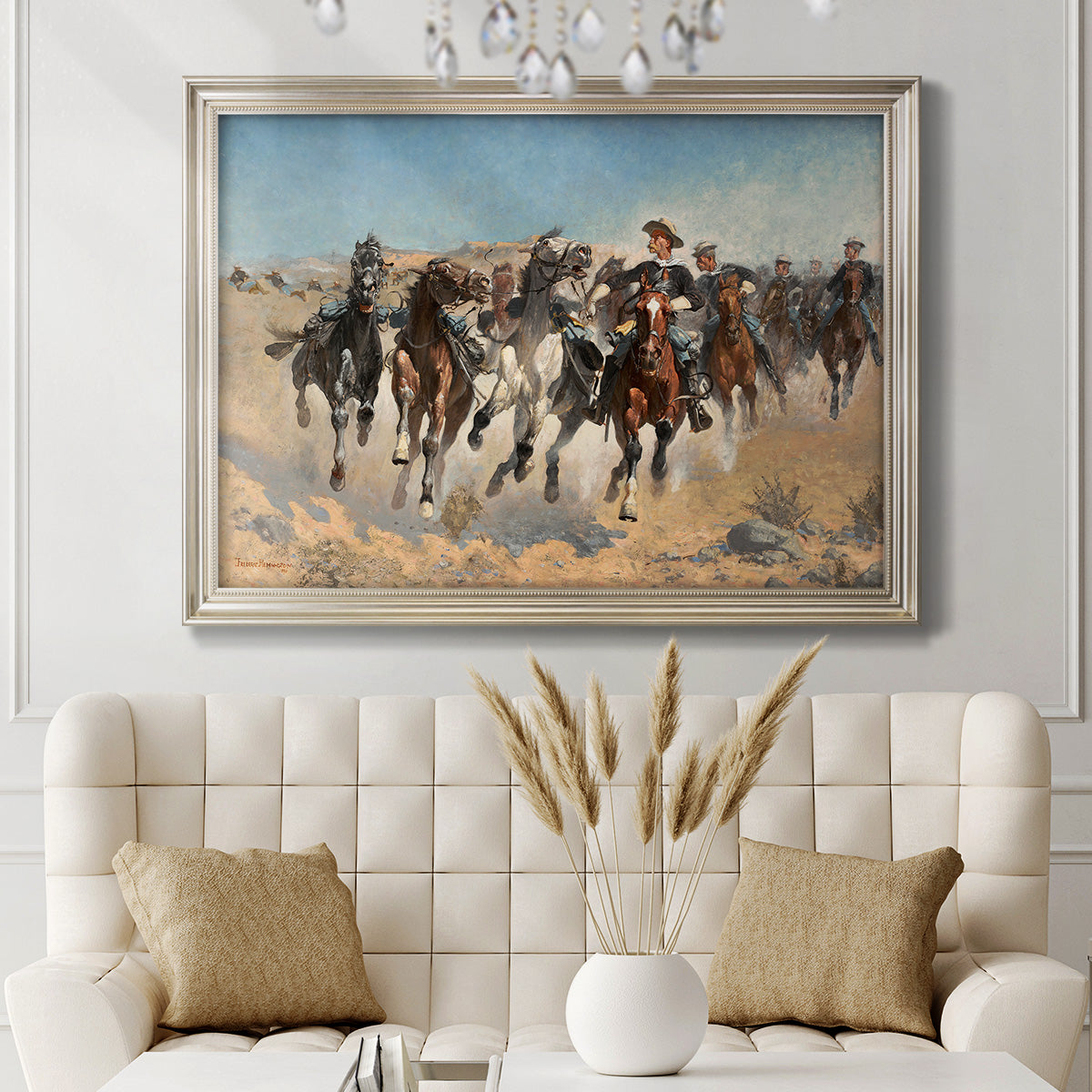 Impressionist western action scene by Frederic Remington in an ornate champagne frame displayed in a neutral-toned interior setting.