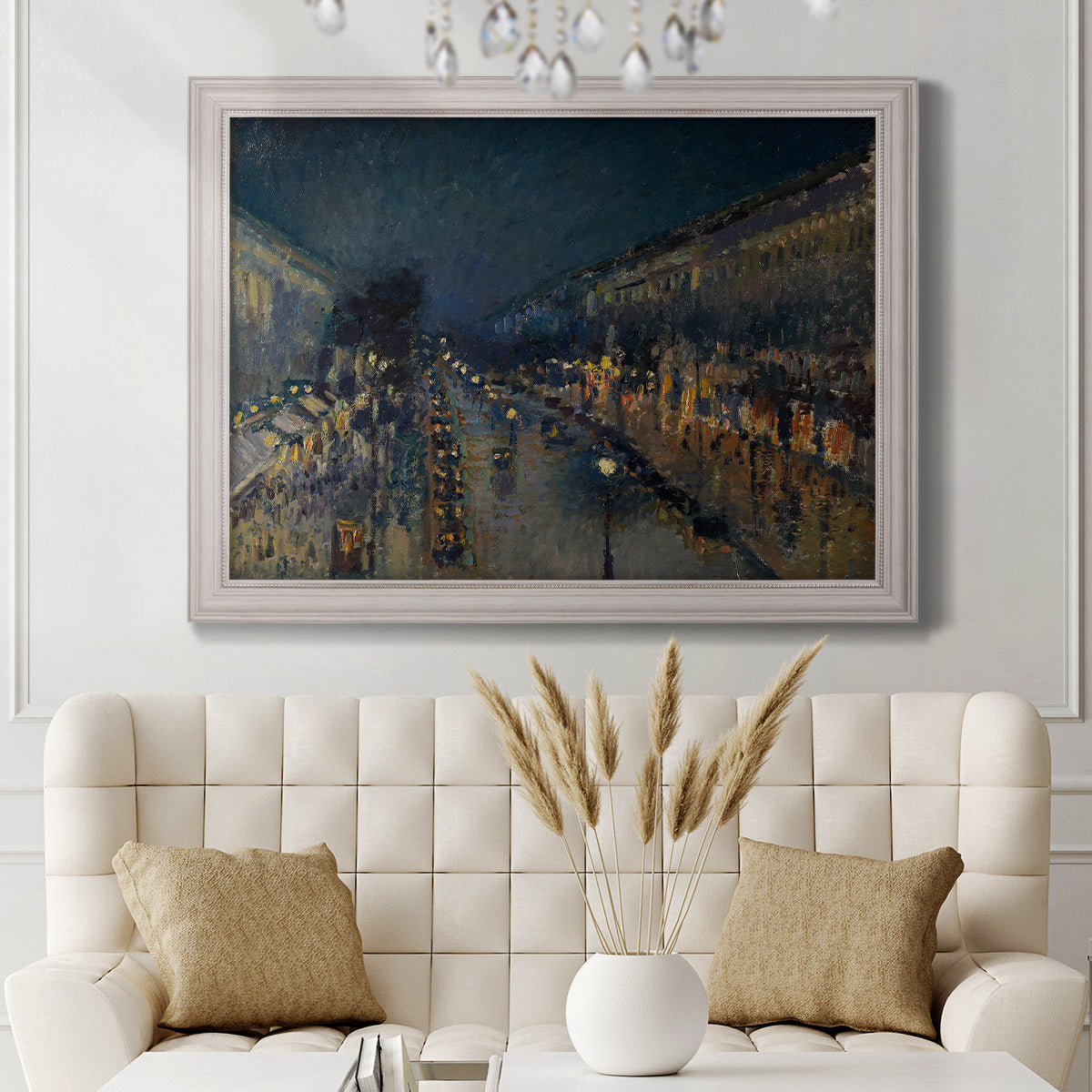 Impressionist nighttime Paris street scene by Camille Pissarro in an ornate weathered white frame displayed in a neutral-toned interior setting.