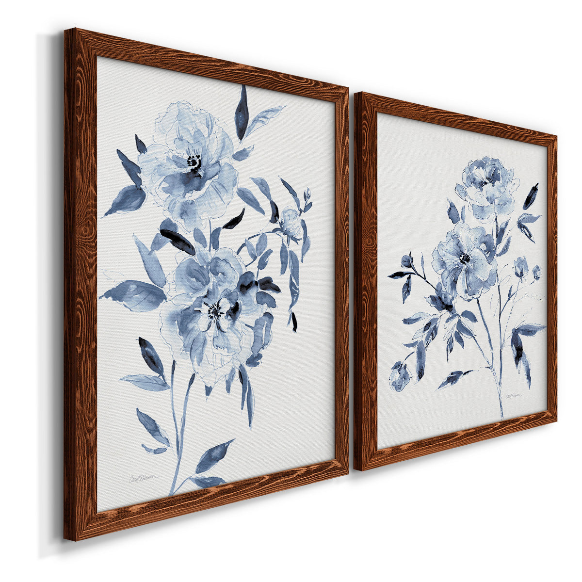 Angled view of a set of two maple barnwood framed canvas prints featuring two expressive watercolor botanical paintings featuring loose blue flowers and leafy branches.