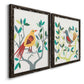 Angled view of a set of two black barnwood framed canvas prints featuring two modern folk-art bird illustrations featuring stylized colorful birds perched among leafy branches.
