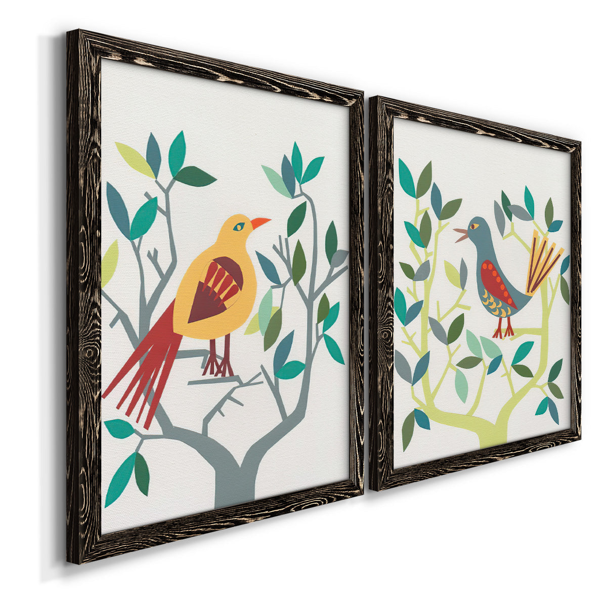 Angled view of a set of two black barnwood framed canvas prints featuring two modern folk-art bird illustrations featuring stylized colorful birds perched among leafy branches.
