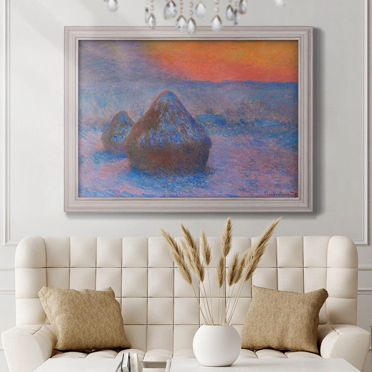 Impressionist haystack scene at sunset by Claude Monet in an ornate weathered white frame displayed in a neutral-toned interior setting.
