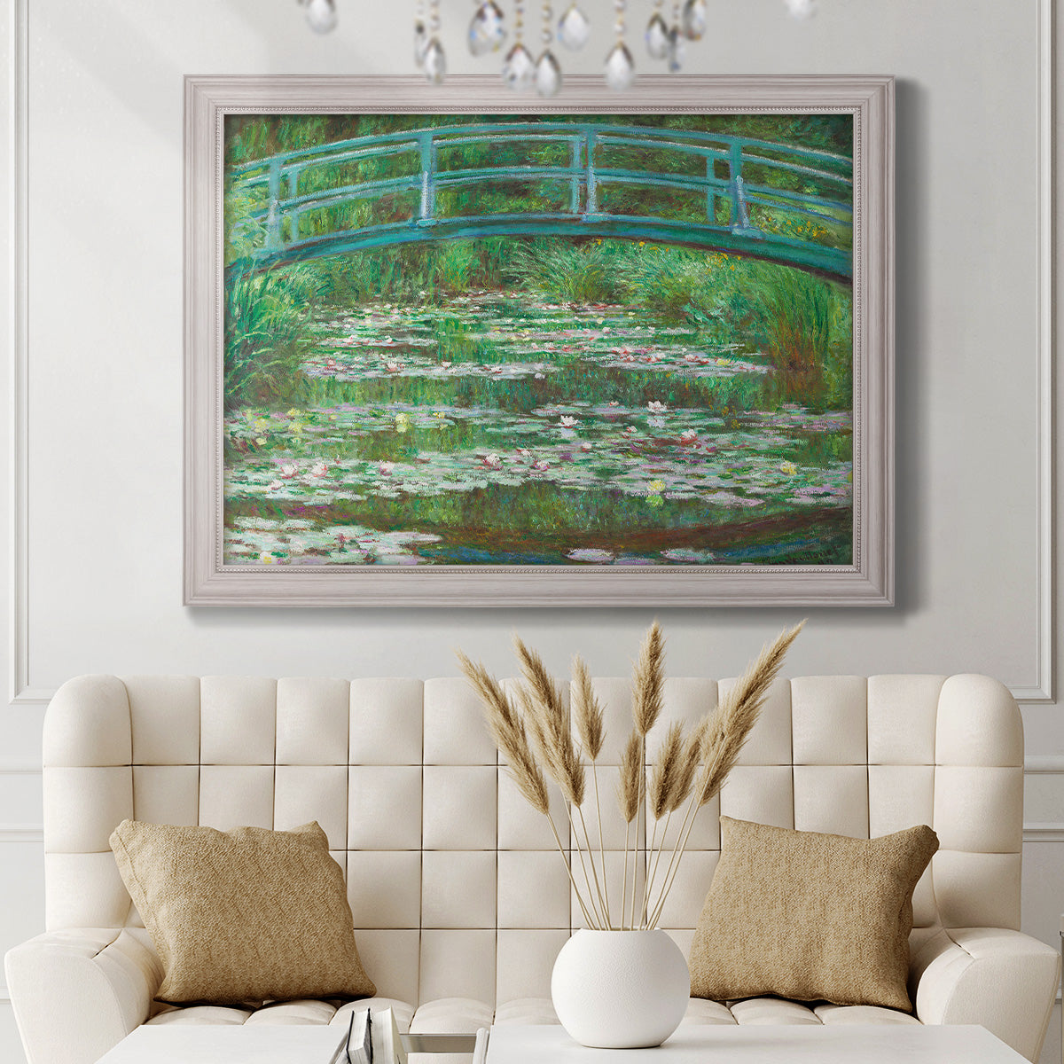Impressionist garden scene with Japanese bridge and water lilies by Claude Monet in an ornate weathered white frame displayed in a neutral-toned interior setting.