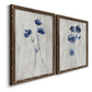 Angled view of a set of two walnut barnwood framed canvas prints featuring two rustic monochrome botanical paintings featuring blue wildflower stems on weathered neutral paper.