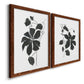 Angled view of a set of two maple barnwood framed canvas prints featuring two minimalist botanical prints featuring black leafy vine silhouettes.