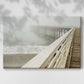 Fog envelops a pier while waves gently lap against the shore on a tranquil morning