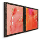 Angled view of a set of two black barnwood framed canvas prints featuring two glamorous fluid abstracts featuring luminous coral orange and pink color fields with gold flecks.