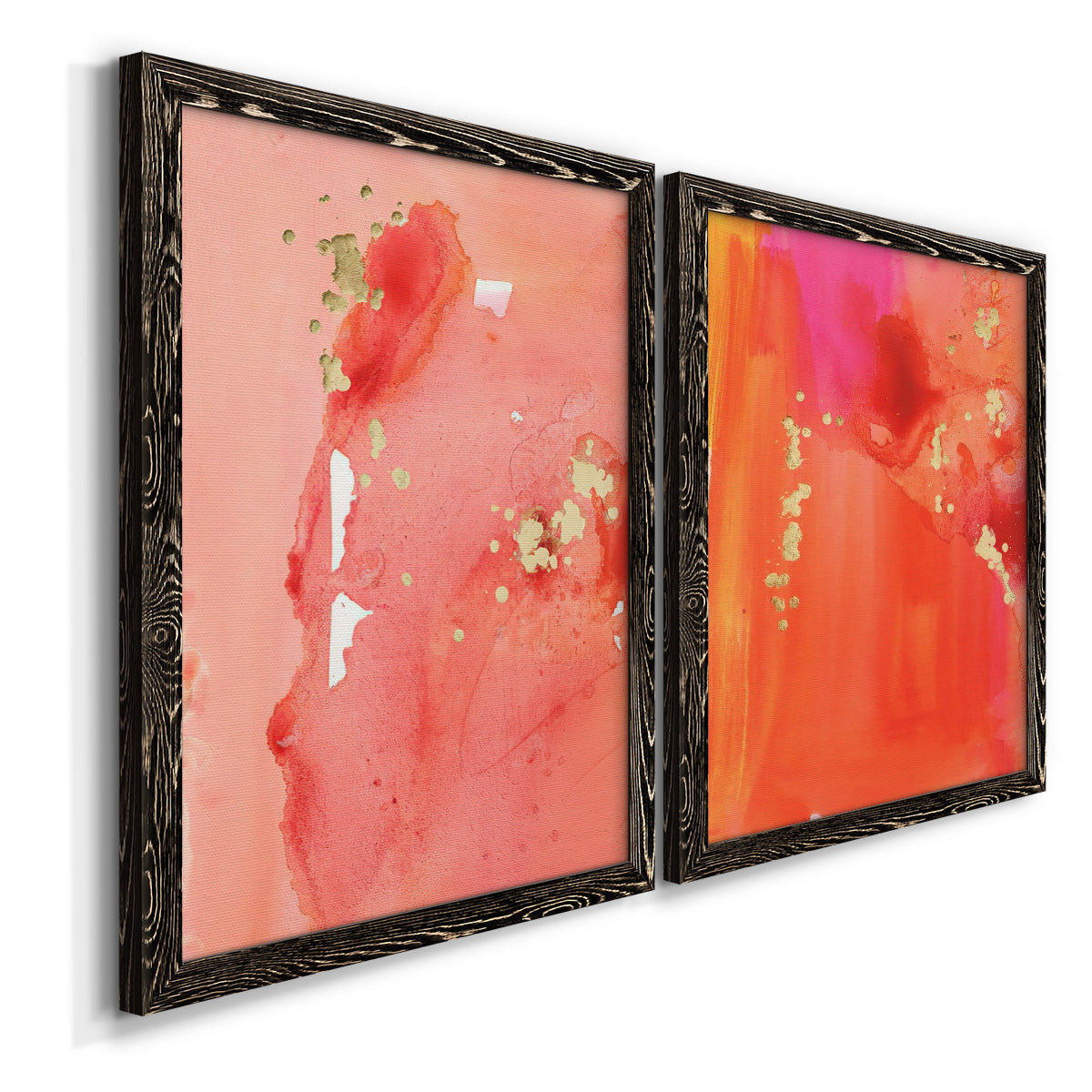 Angled view of a set of two black barnwood framed canvas prints featuring two glamorous fluid abstracts featuring luminous coral orange and pink color fields with gold flecks.