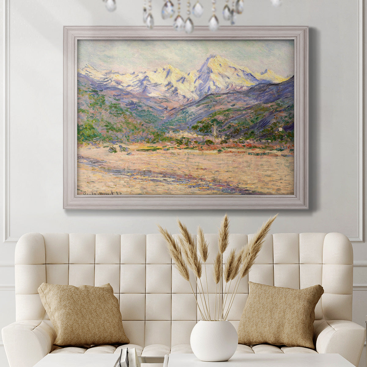 Impressionist valley landscape in southern France by Claude Monet in an ornate weathered white frame displayed in a neutral-toned interior setting.