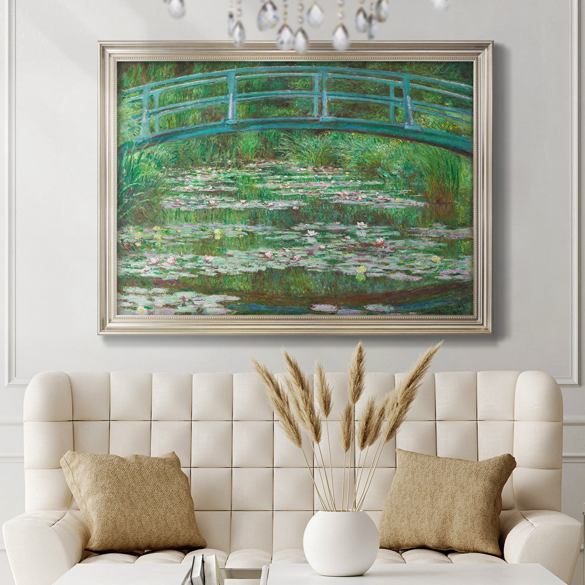 Impressionist garden scene with Japanese bridge and water lilies by Claude Monet in an ornate champagne frame displayed in a neutral-toned interior setting.