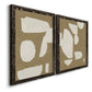 Angled view of a set of two black barnwood framed canvas prints featuring two bold minimalist shape abstracts featuring irregular white cutout-like shapes on taupe grounds.