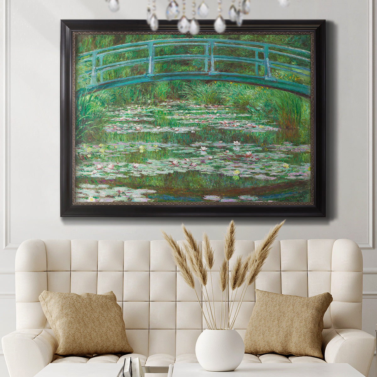 Impressionist garden scene with Japanese bridge and water lilies by Claude Monet in an ornate black frame with gilded inner detail displayed in a neutral-toned interior setting.