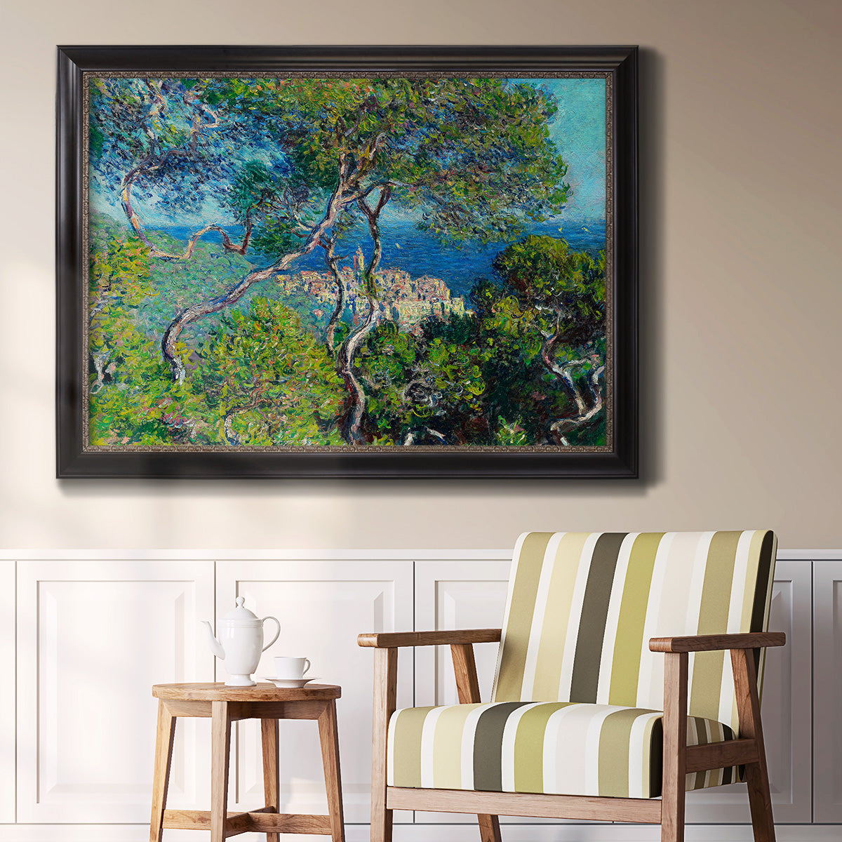 Impressionist Mediterranean coastal landscape by Claude Monet in an ornate black frame with gilded inner detail displayed in a light-toned interior setting.