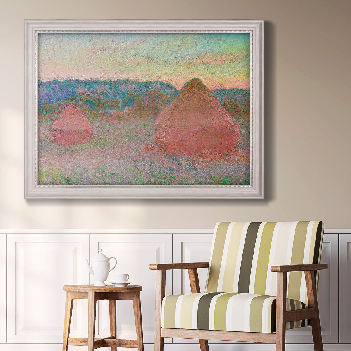 Impressionist haystack series landscape by Claude Monet in an ornate weathered white frame displayed in a light-toned interior setting.