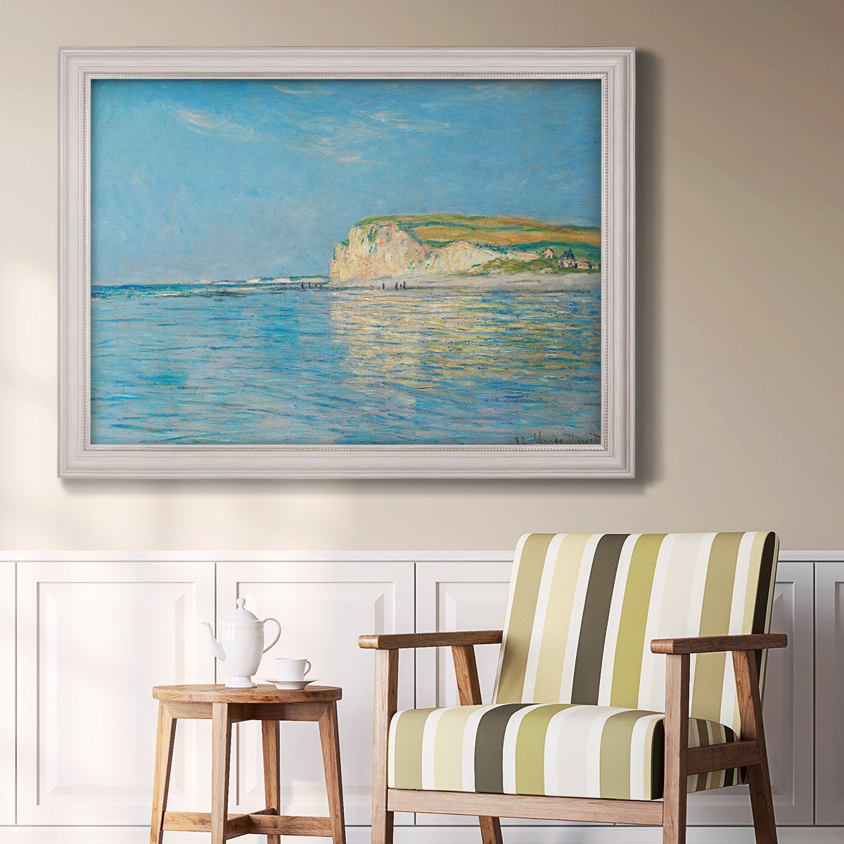 Impressionist coastal low-tide seascape at Pourville by Claude Monet in an ornate weathered white frame displayed in a light-toned interior setting.