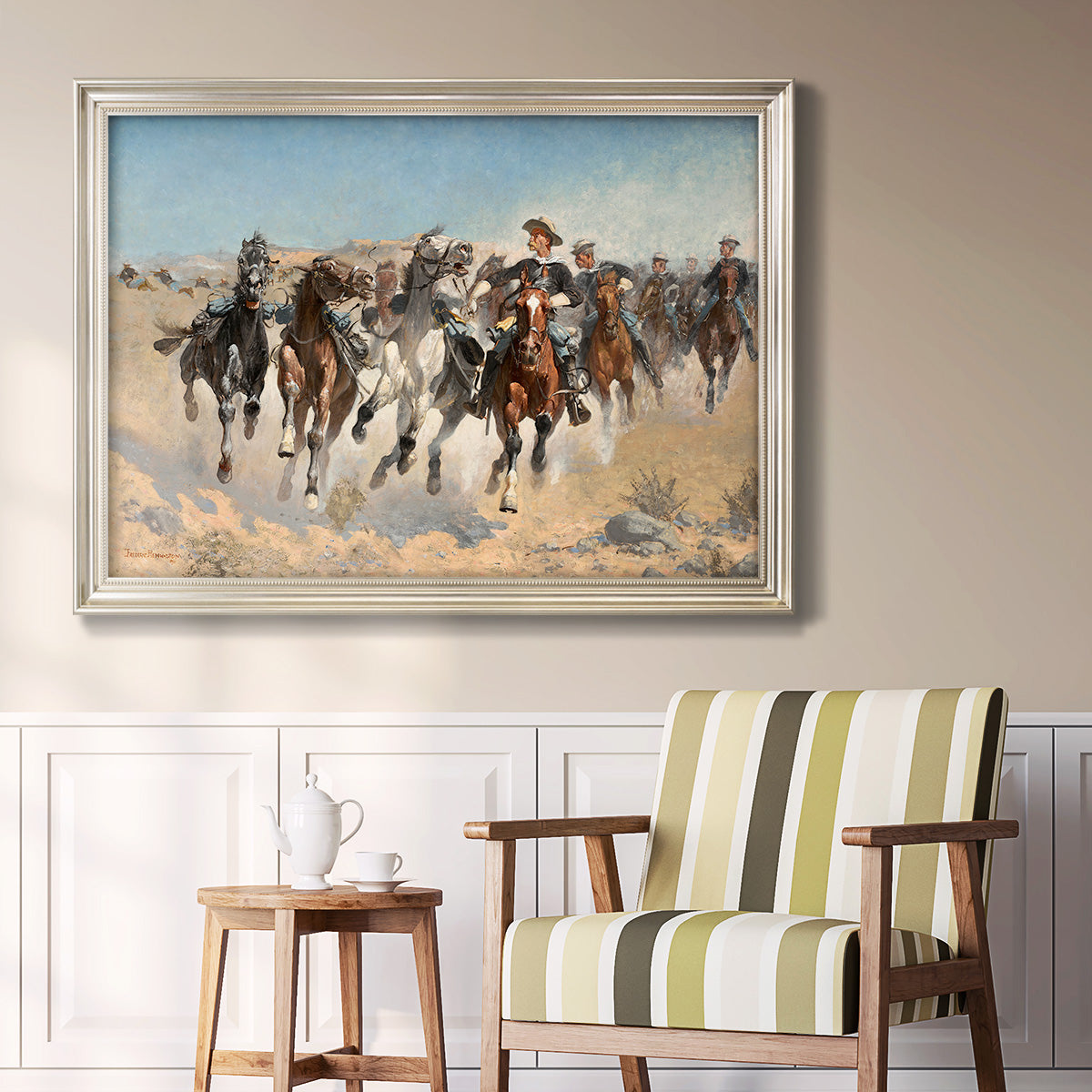 Impressionist western action scene by Frederic Remington in an ornate champagne frame displayed in a light-toned interior setting.