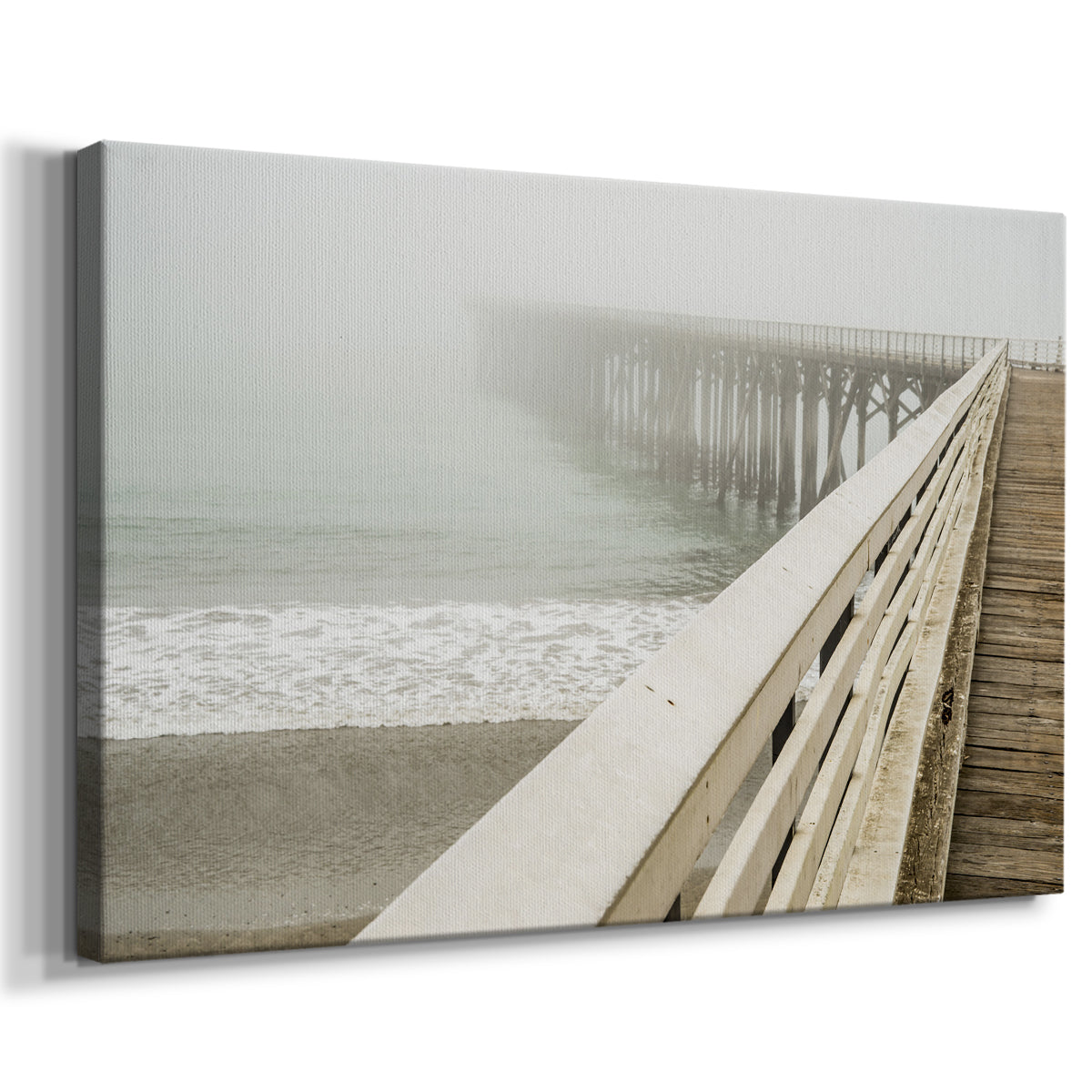 Fog envelops a pier while waves gently lap against the shore on a tranquil morning