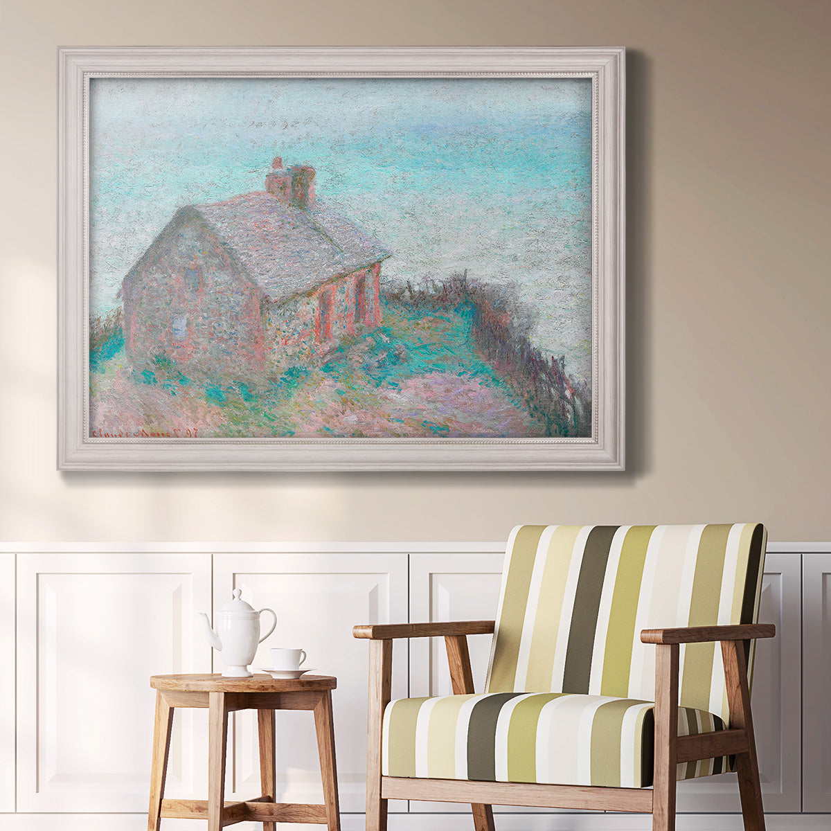 Impressionist coastal building landscape by Claude Monet in an ornate weathered white frame displayed in a light-toned interior setting.