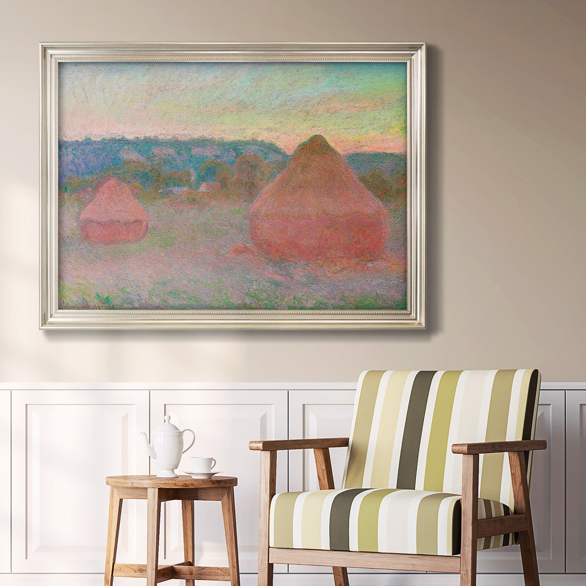 Impressionist haystack series landscape by Claude Monet in an ornate champagne frame displayed in a light-toned interior setting.