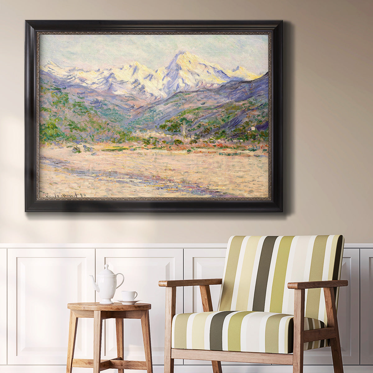 Impressionist valley landscape in southern France by Claude Monet in an ornate black frame with gilded inner detail displayed in a light-toned interior setting.