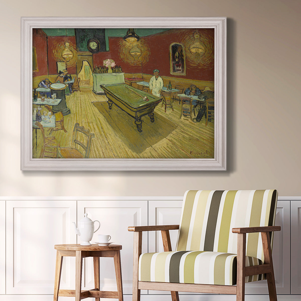 Impressionist interior of a night café by Vincent van Gogh in an ornate weathered white frame displayed in a light-toned interior setting.