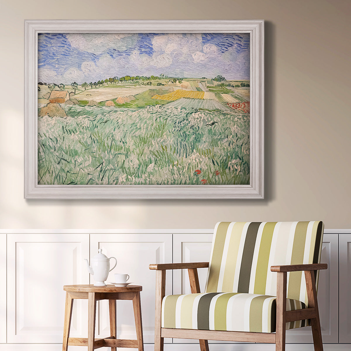 Impressionist countryside landscape near Auvers by Vincent van Gogh in an ornate weathered white frame displayed in a light-toned interior setting.