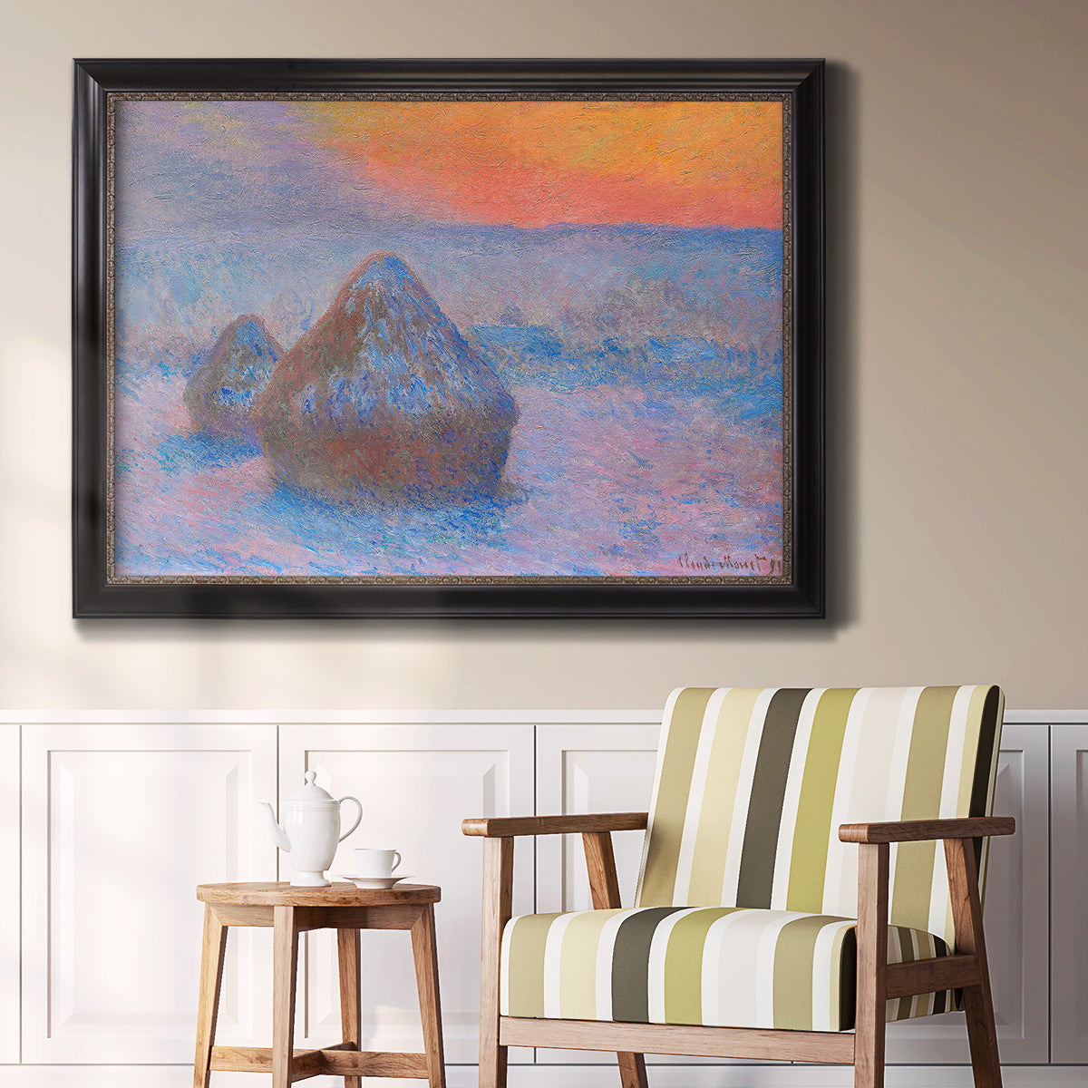 Impressionist haystack scene at sunset by Claude Monet in an ornate black frame with gilded inner detail displayed in a light-toned interior setting.