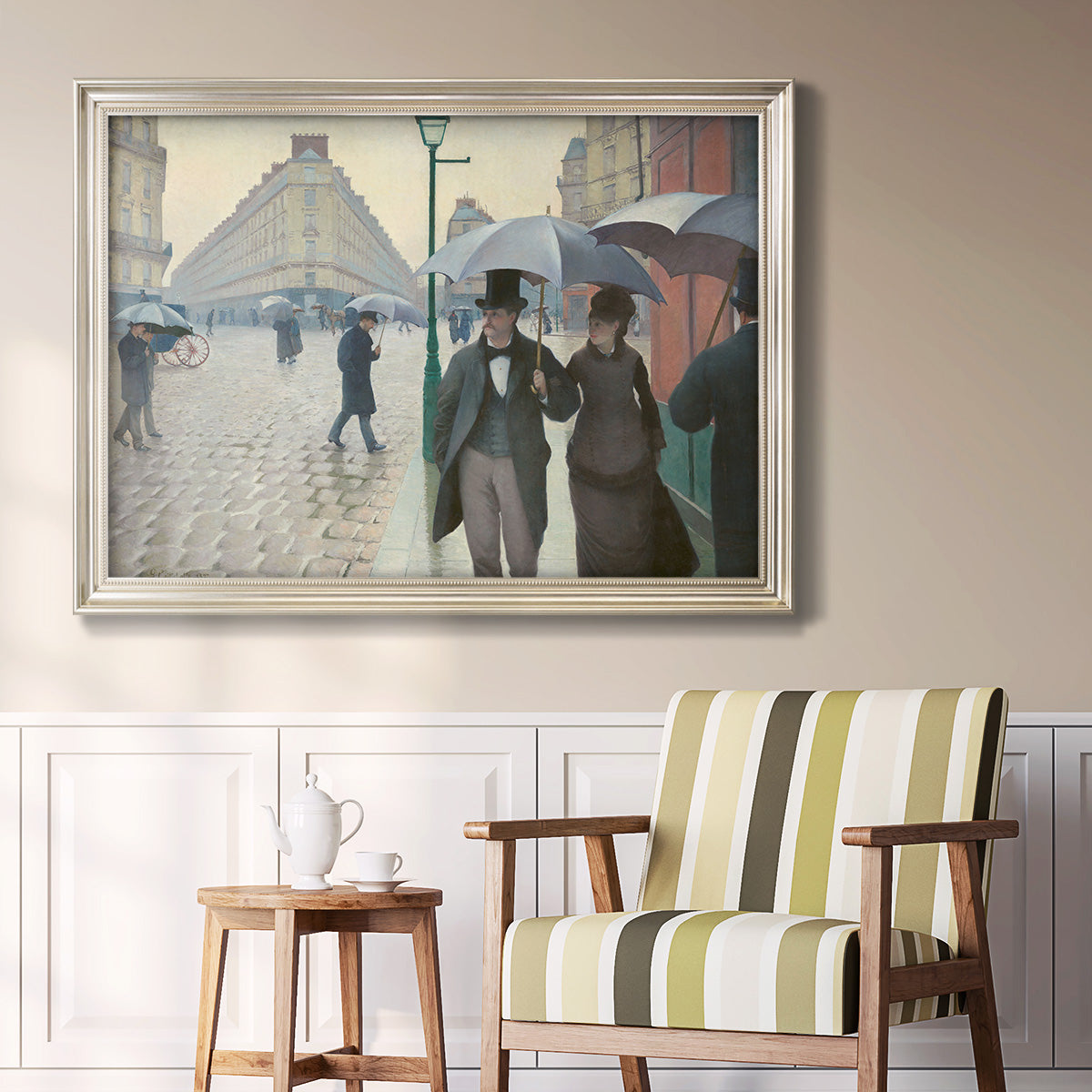 Impressionist urban street scene in the rain by Gustave Caillebotte in an ornate champagne frame displayed in a light-toned interior setting.