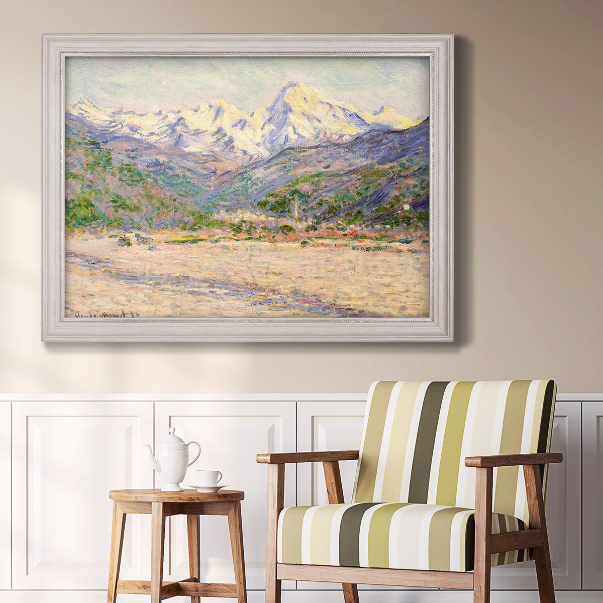 Impressionist valley landscape in southern France by Claude Monet in an ornate weathered white frame displayed in a light-toned interior setting.