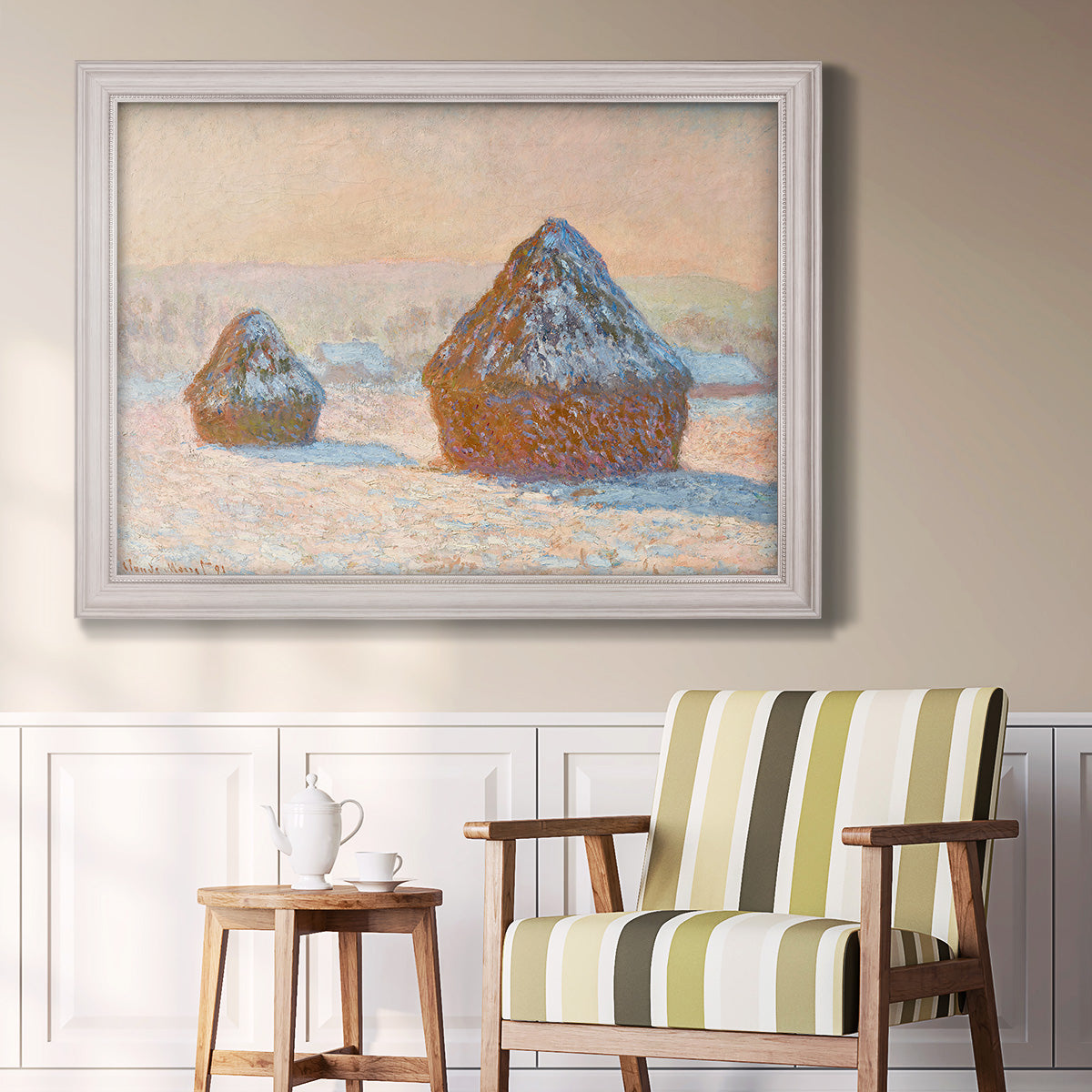 Impressionist winter haystack scene by Claude Monet in an ornate weathered white frame displayed in a light-toned interior setting.