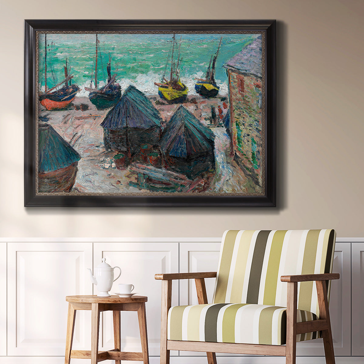 Impressionist coastal beach scene with boats by Claude Monet in an ornate black frame with gilded inner detail displayed in a light-toned interior setting.
