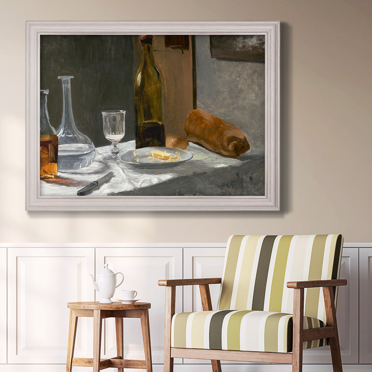 Impressionist still life with wine and bread by Claude Monet in an ornate weathered white frame displayed in a light-toned interior setting.