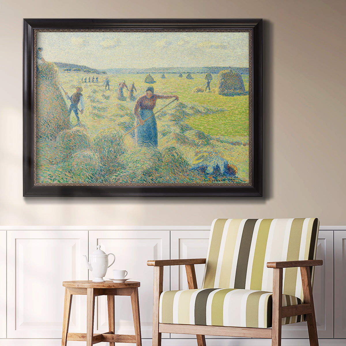 Impressionist rural hay harvest landscape by Camille Pissarro in an ornate black frame with gilded inner detail displayed in a light-toned interior setting.