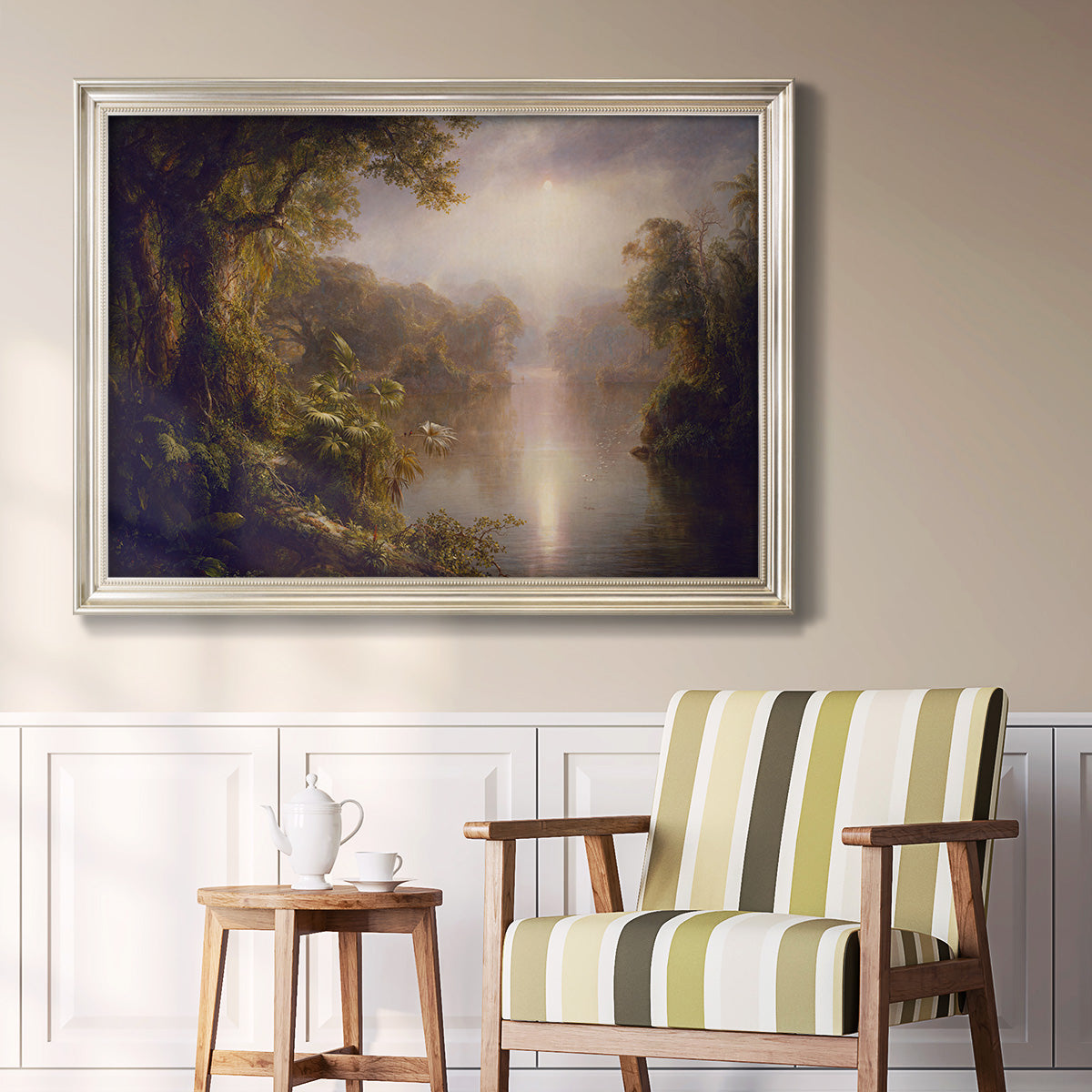 Luminous romantic landscape painting by Frederic Edwin Church in an ornate champagne frame displayed in a light-toned interior setting.