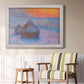Impressionist haystack scene at sunset by Claude Monet in an ornate weathered white frame displayed in a light-toned interior setting.
