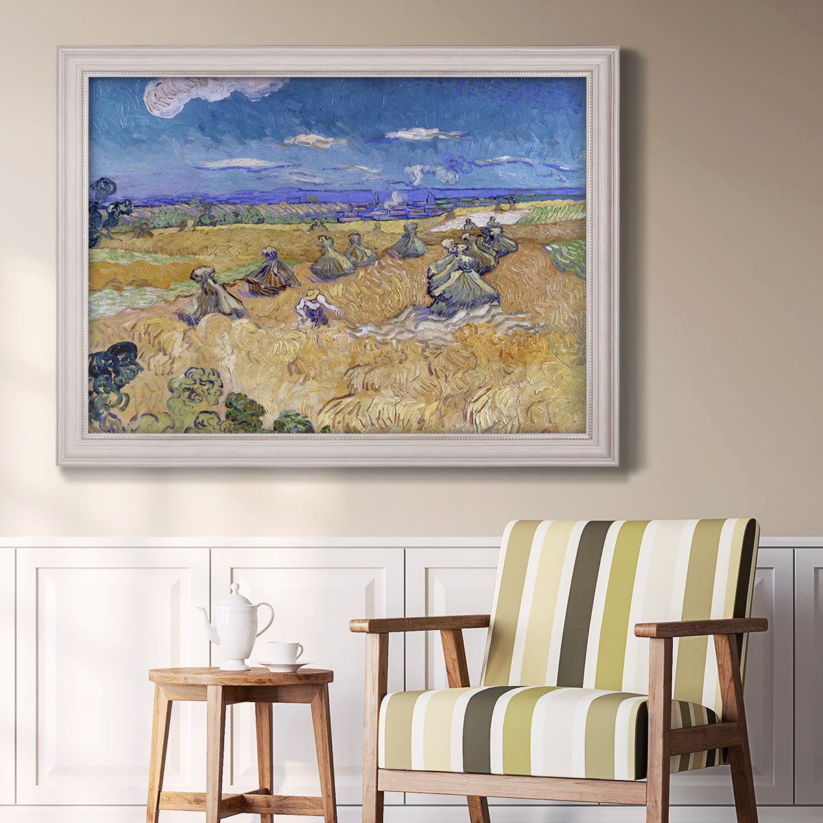Impressionist wheat harvest scene by Vincent van Gogh in an ornate weathered white frame displayed in a light-toned interior setting.