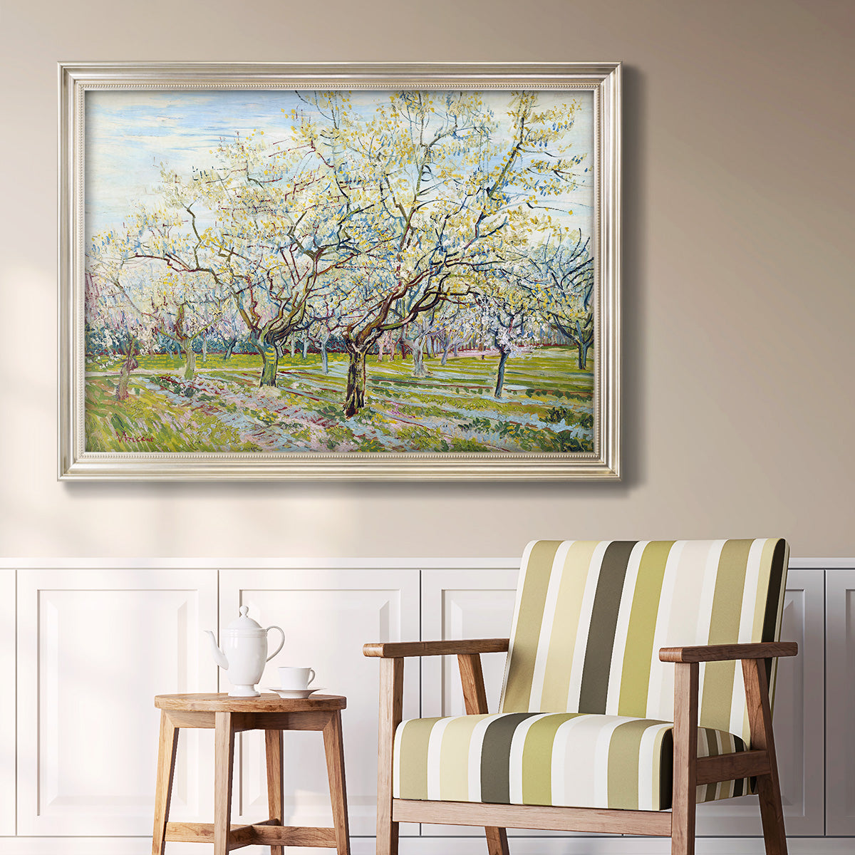 Impressionist white-blossomed orchard landscape by Vincent van Gogh in an ornate champagne frame displayed in a light-toned interior setting.