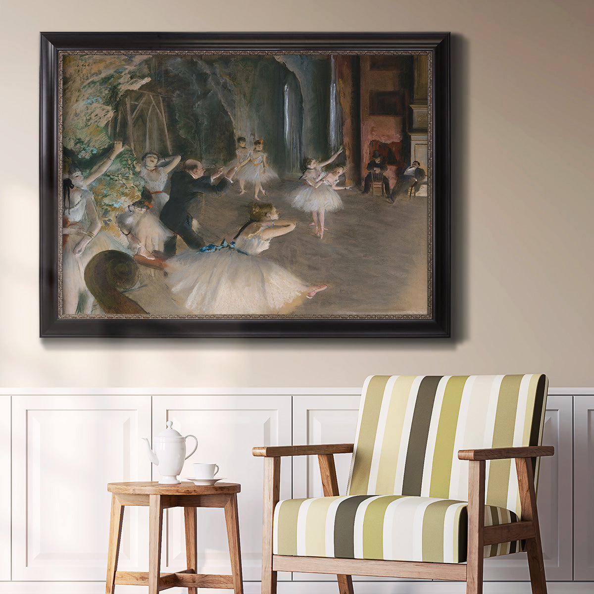 Impressionist backstage ballet scene by Edgar Degas in an ornate black frame with gilded inner detail displayed in a light-toned interior setting.