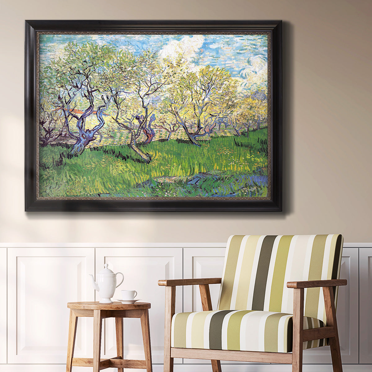 Impressionist spring orchard landscape by Vincent van Gogh in an ornate black frame with gilded inner detail displayed in a light-toned interior setting.